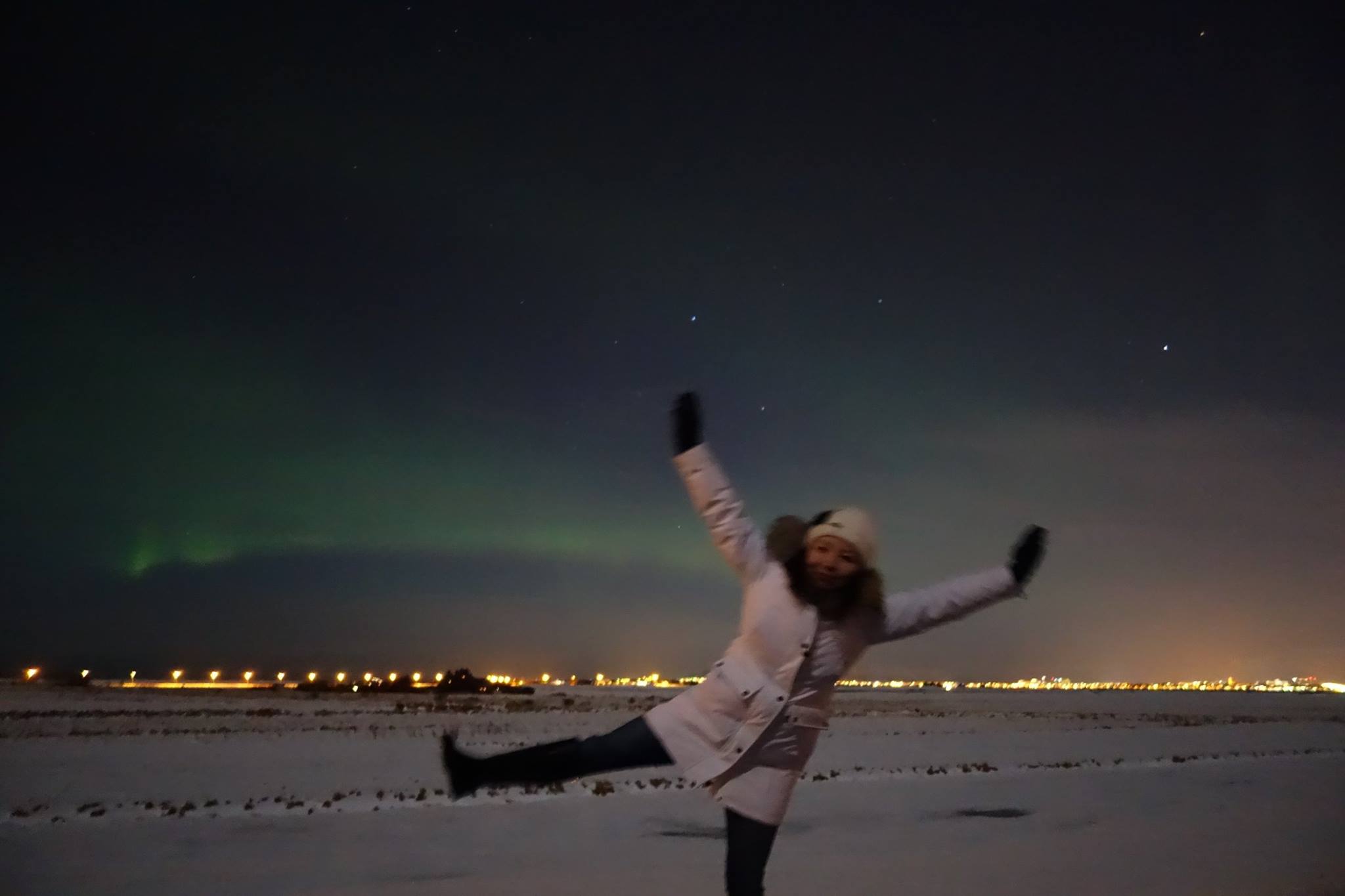 Jen in Iceland, dancing in front of an aurora